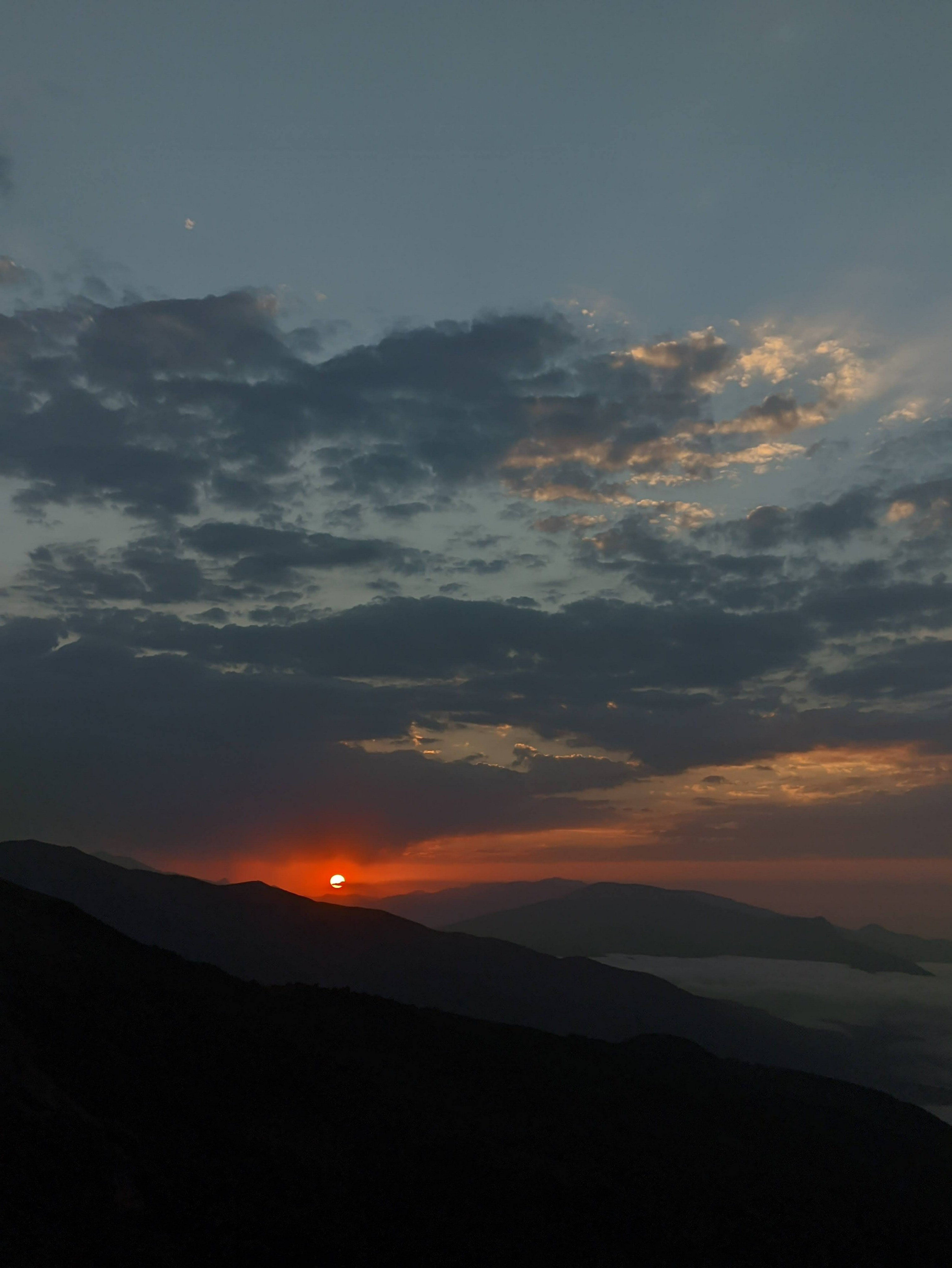 Crimson sunset orb over mountain silhouettes